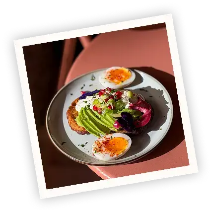 Polaroid-style photo of an avocado toast with cream cheese and pomegranate seeds, served with a soft-boiled egg at Pamela's Bar in Nice.